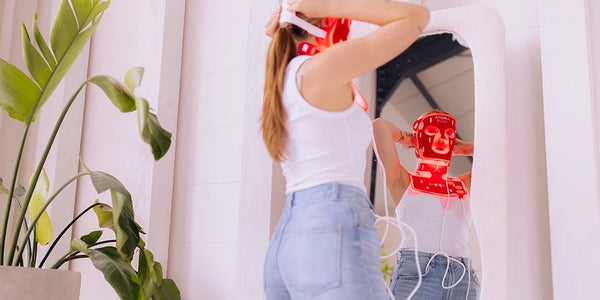 Vrouw draagt het Liroma LED masker voor rood licht therapie voor de spiegel
