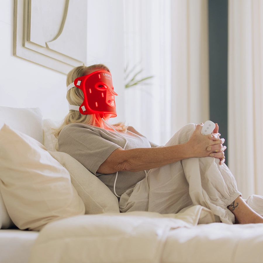 Vrouw ontspant op bed met het Liroma LED masker voor het gezicht